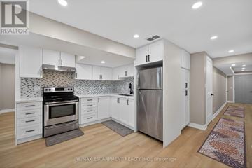 Hamilton (Mount Hope) apartment for rent - A kitchen with white cabinets and a tile backsplash.