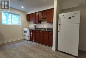Newmarket (Huron Heights-Leslie Valley) apartment for rent - A kitchen with brown cabinets and a white fridge.