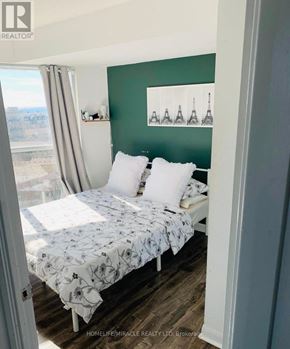 Toronto (Niagara) condo for rent - A bedroom with a bed and a window with curtains.
