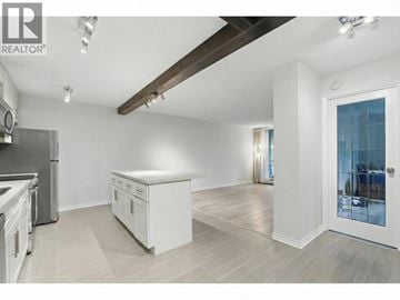 North Vancouver apartment for rent - A spacious kitchen with white cabinets and a wooden ceiling beam.