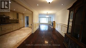 Toronto (Newtonbrook East) apartment for rent - A spacious room with wooden floors and a kitchen area with a counter and cabinets.