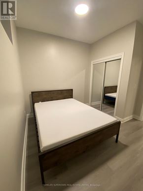 Fort Erie (Central) apartment for rent - A bedroom with a bed, wooden headboard, and a mirror.
