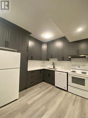Fort Erie (Central) apartment for rent - A modern kitchen with white appliances and wooden floors.