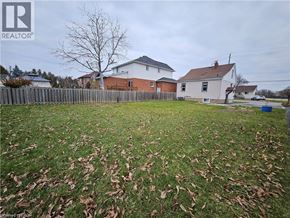 Hamilton apartment for rent - A grassy yard with a fence and two houses in the background.