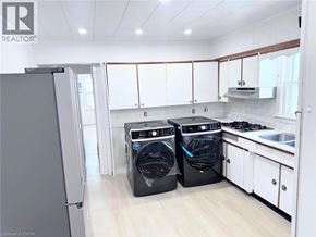 Fort Erie apartment for rent - A modern kitchen with a refrigerator, washing machine, and dryer.
