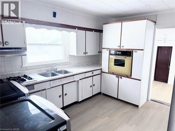 Fort Erie apartment for rent - A kitchen with white cabinets and a black stove top oven.
