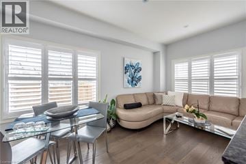 Stoney Creek townhouse for rent - A well-lit living room with a glass dining table and chairs, a sofa, and a coffee table.