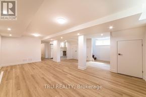 Ottawa apartment for rent - A spacious room with wooden flooring and white walls, with a logo that reads "TRU REALTY, Brokerage" in the bottom right corner.