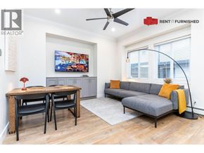 Vancouver apartment for rent - A living room with a grey couch, a wooden table with two chairs, and a painting on the wall.