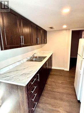 Barrie (Holly) apartment for rent - A kitchen with dark wood cabinets and a marble countertop.