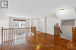 Ottawa townhouse for rent - A spacious room with wooden floors and white walls, featuring a staircase with a wooden banister.