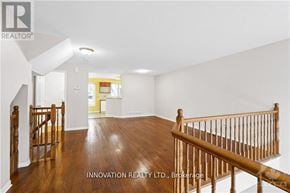 Ottawa townhouse for rent - A spacious room with wooden floors and a staircase with wooden railings.