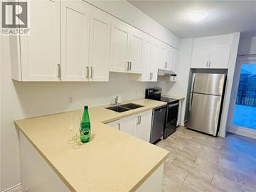 Waterloo townhouse for rent - A kitchen with white cabinets and a green bottle on the counter.