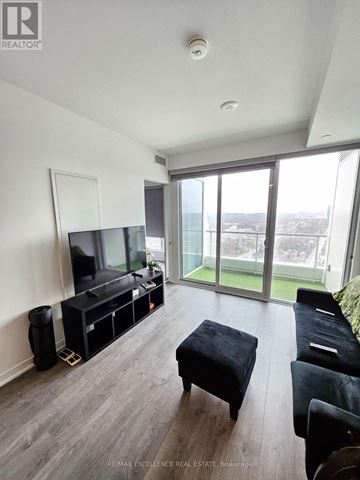 Barrie (City Centre) condo for rent - A living room with a television and a glass door.