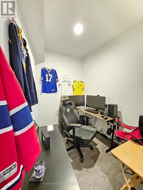 Barrie (City Centre) condo for rent - A room with a desk, chairs, and sports jerseys hanging on the wall.