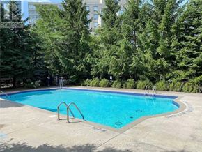 Vaughan (Crestwood-Springfarm-Yorkhill) condo for rent - A swimming pool surrounded by trees and a building in the background.
