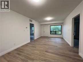 Windsor condo for rent - A spacious room with wooden flooring and white walls.