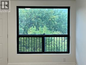 Windsor condo for rent - A window with a view of trees and a balcony.