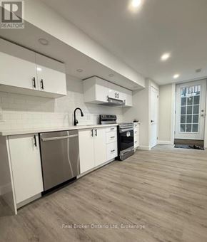 Barrie (Georgian Drive) apartment for rent - A modern kitchen with white cabinets and a wooden floor.