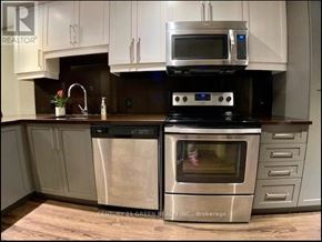 Waterloo condo for rent - A kitchen with a stove top oven and microwave above it.