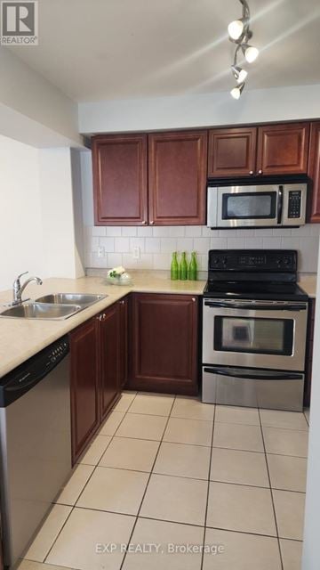 Ajax (South West) townhouse for rent - A kitchen with brown cabinets and a black stove top oven.