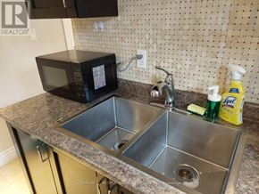 Toronto (Woburn) apartment for rent - A kitchen counter with a microwave, sink, and cleaning supplies.