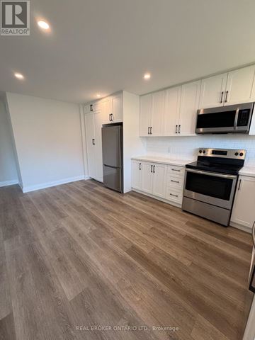 Oshawa (Donevan) apartment for rent - A kitchen with white cabinets and a wooden floor.
