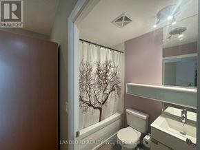 Toronto (Bay Street Corridor) condo for rent - A bathroom with a toilet, sink, and a window with a tree outside.