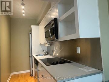 Toronto (Bay Street Corridor) condo for rent - A kitchen with a stainless steel refrigerator and white cabinets.