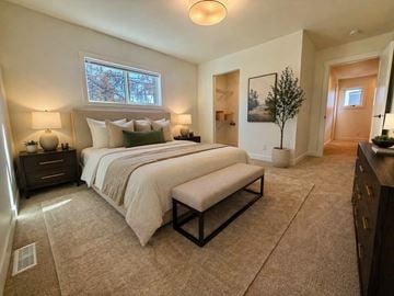 Edmonton apartment for rent - A bedroom with a large bed and a bench in front of it.