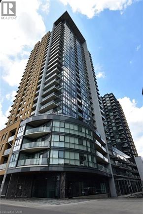 Kitchener condo for rent - A tall building with a glass facade stands under a blue sky.