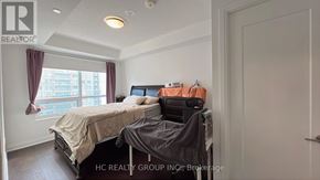 Richmond Hill (Doncrest) condo for rent - A bedroom with a bed, a desk with a printer, and a window with curtains.