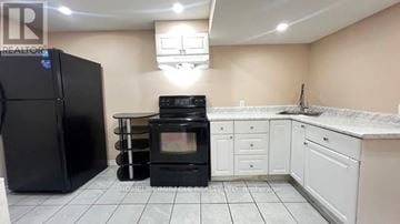 Toronto (Rouge) townhouse for rent - A kitchen with black appliances and white cabinets.