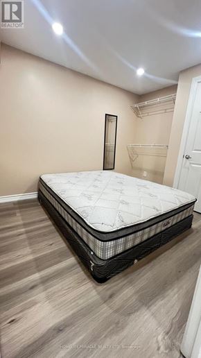 Toronto (Rouge) townhouse for rent - A bed with a white mattress and black frame is in a room with light beige walls.