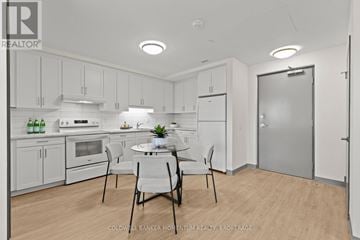 Thorold (Thorold Downtown) multi-family for rent - A modern kitchen with white cabinets and a dining table set for two.