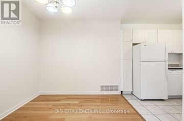 Toronto (Don Valley Village) townhouse for rent - A white kitchen with a refrigerator and wooden flooring.