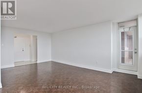 Toronto (Don Valley Village) condo for rent - A spacious room with wooden flooring and white walls, with a door on the left and a window on the right.
