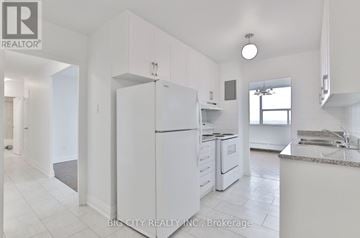 Toronto (Don Valley Village) condo for rent - A white kitchen with a refrigerator, sink, and cabinets.