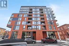 Ottawa condo for rent - A modern multi-story building with a red brick facade and a sign for Century 21 Synergy Realty Inc. in the foreground.