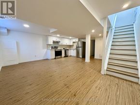 Ottawa apartment for rent - A spacious room with wooden flooring and a staircase on the right side.