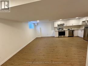 Ottawa apartment for rent - A spacious room with wooden flooring and a kitchen area in the background.