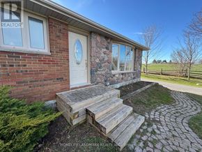Clarington apartment for rent - A house with a brown roof and a white door is surrounded by green grass.