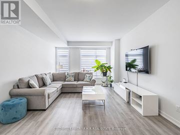Toronto (Bendale) townhouse for rent - A modern living room with a grey sofa, a white coffee table, and a television on the wall.