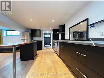 Toronto (Kennedy Park) apartment for rent - A modern kitchen with wooden floors and black cabinets.