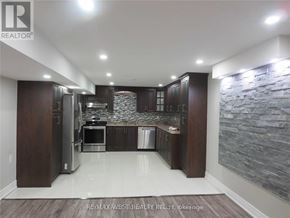 Brampton (Toronto Gore Rural Estate) apartment for rent - A modern kitchen with dark wood cabinets and a stone wall backsplash.