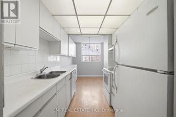 Brampton (Queen Street Corridor) condo for rent - A white kitchen with a sink and refrigerator.