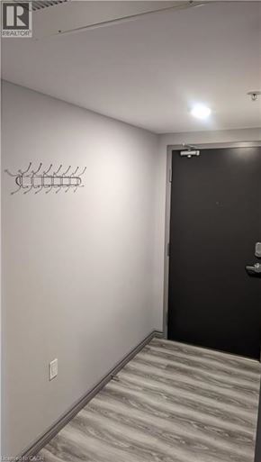 Waterloo condo for rent - A hallway with a black door and a coat rack on the wall.