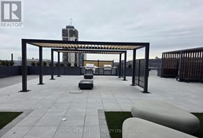 Hamilton (Corktown) condo for rent - A large outdoor seating area with a metal pergola and benches.