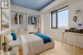 Ottawa apartment for rent - A bedroom with a bed, desk, and clothing rack.
