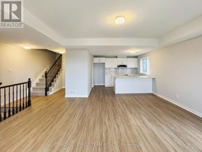Ottawa townhouse for rent - A spacious room with wooden flooring and a staircase with black railings.